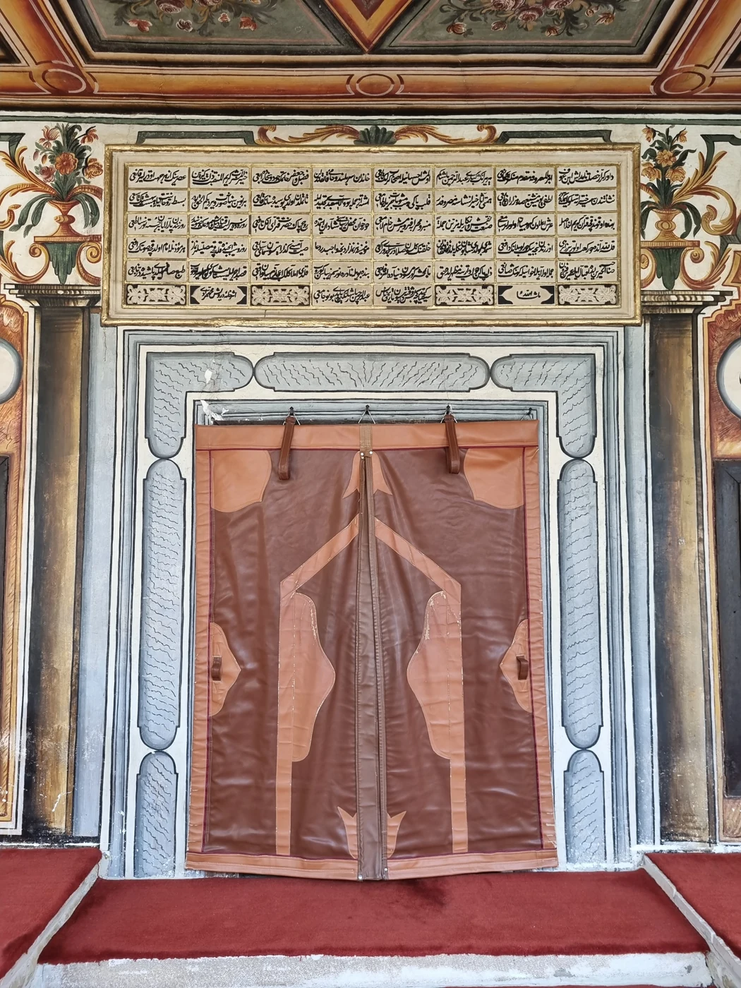 Porta e hyrjes me mbishkrimin dhe dekorimet floreale